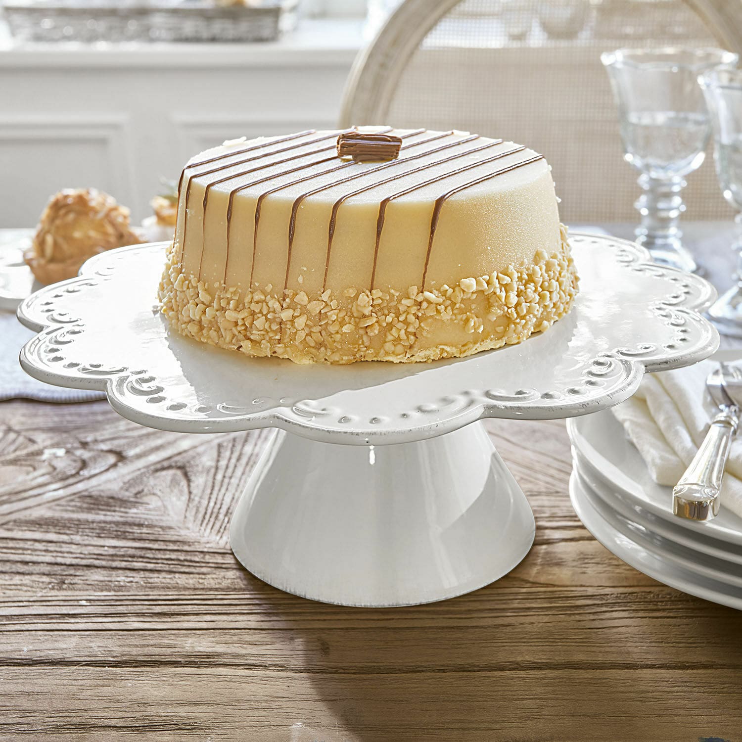 Alzata per dolci Fontienne Alzata per dolci in ceramica bianca con bordo decorativo su tavolo in legno in sala da pranzo