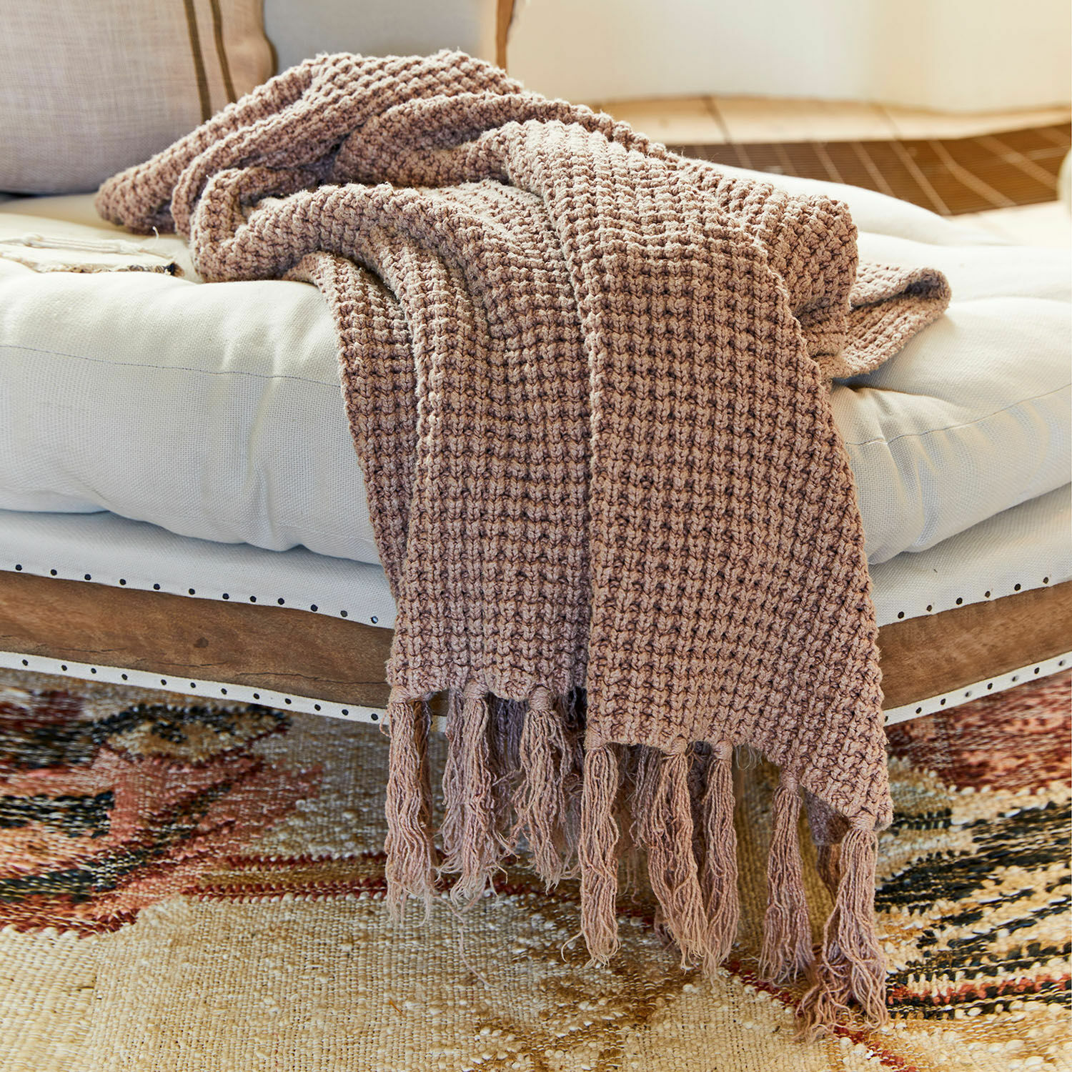 Plaid Kendall Plaid marrone con frange su cuscino bianco su panca in legno, tessuto morbido per soggiorno
