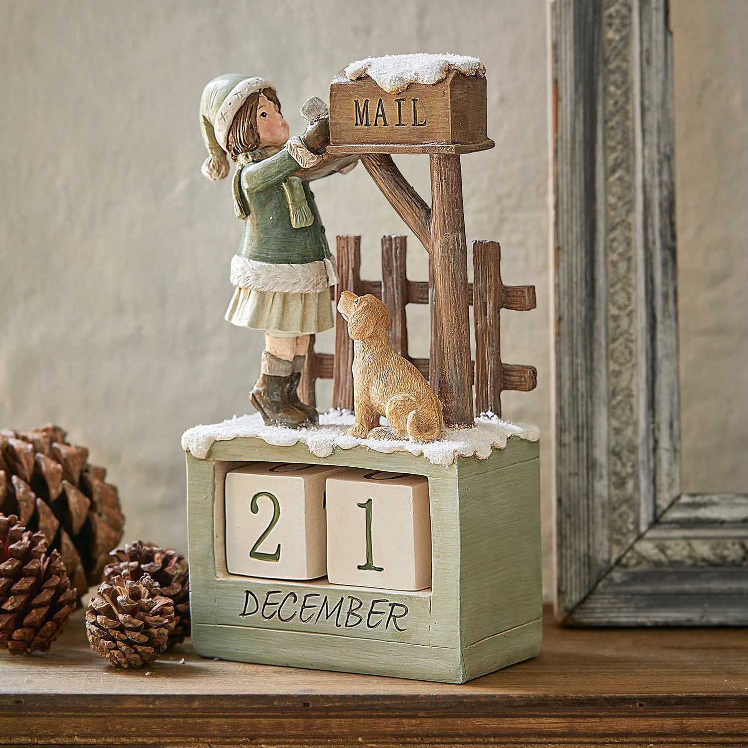 Calendario dell'Avvento in legno con figura di bambina e cane vicino a cassetta postale innevata
