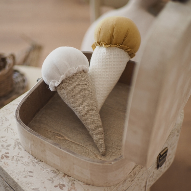 Due coni decorativi in tessuto bianco e senape in una scatola di legno su un tavolo
