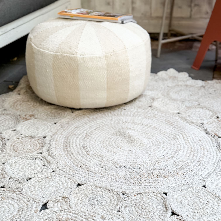 Pouf rotondo bianco in tessuto su tappeto intrecciato chiaro, arredo accogliente