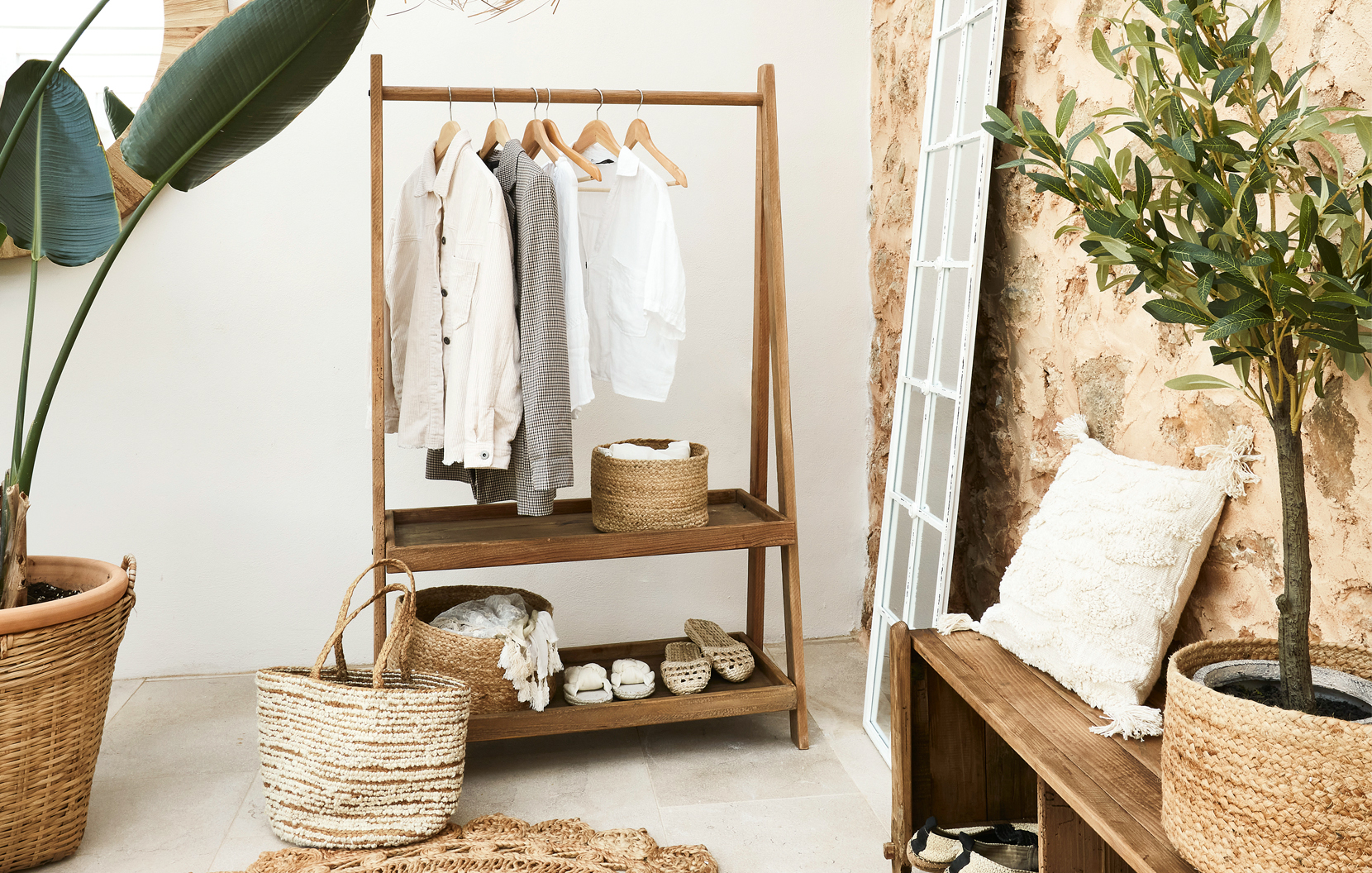Appendiabiti in legno con camicie chiare e cesti di vimini in interno boho