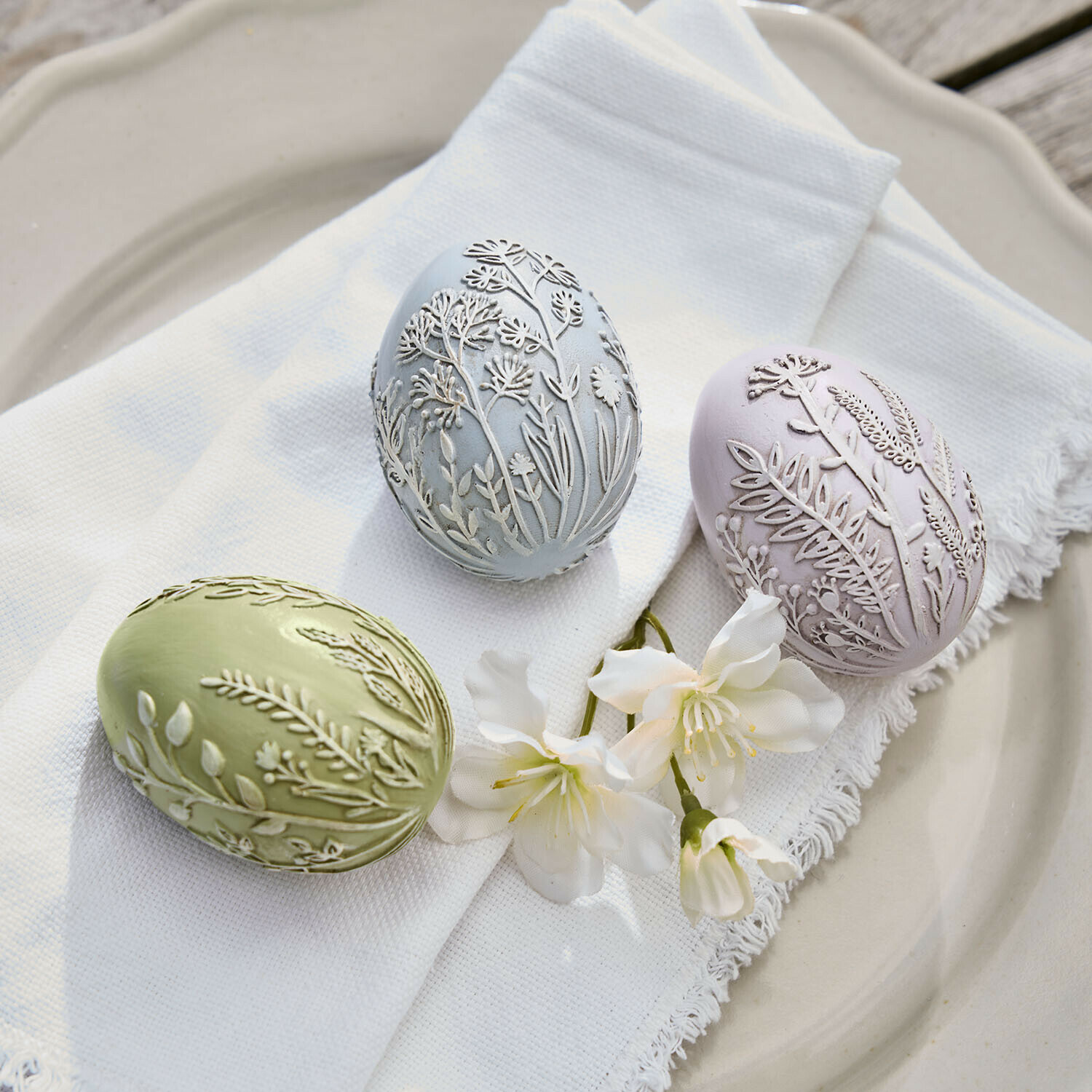Set di 3 uova di Pasqua Fauverine Tre uova decorative pastello con rilievo floreale su tessuto bianco e fiori su piatto