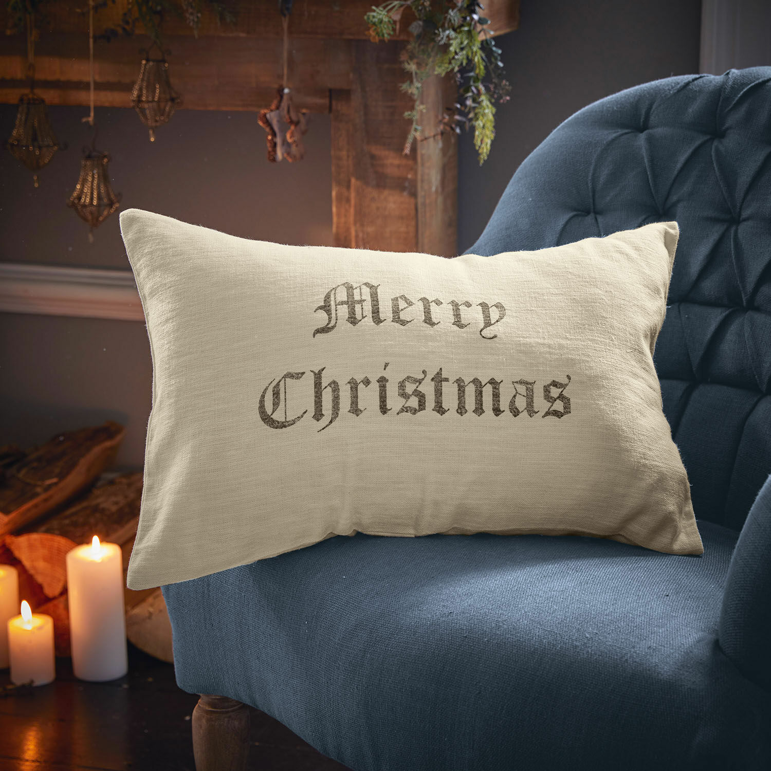 Copricuscino Merry Christmas Cuscino beige in lino con scritta Merry Christmas su poltrona blu, decorazione natalizia