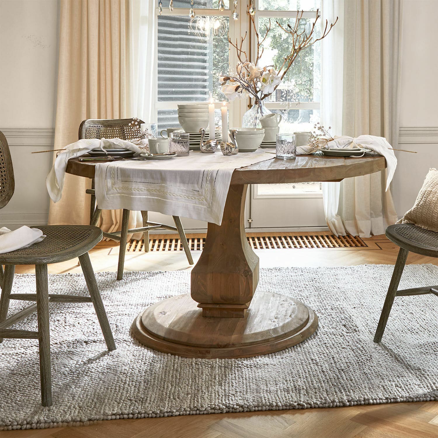 Tavolo Alderwick Tavolo rotondo in legno con tovaglia bianca e decorazioni in una sala da pranzo luminosa e accogliente