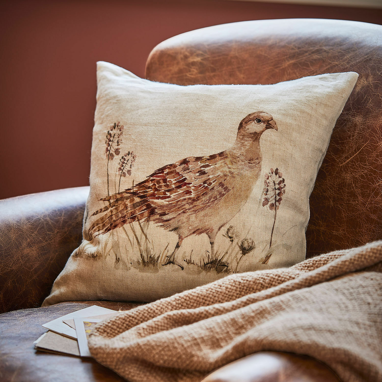 Copricuscino Vivoso Cuscino in lino beige con stampa di uccello marrone su poltrona in pelle marrone per arredo naturale