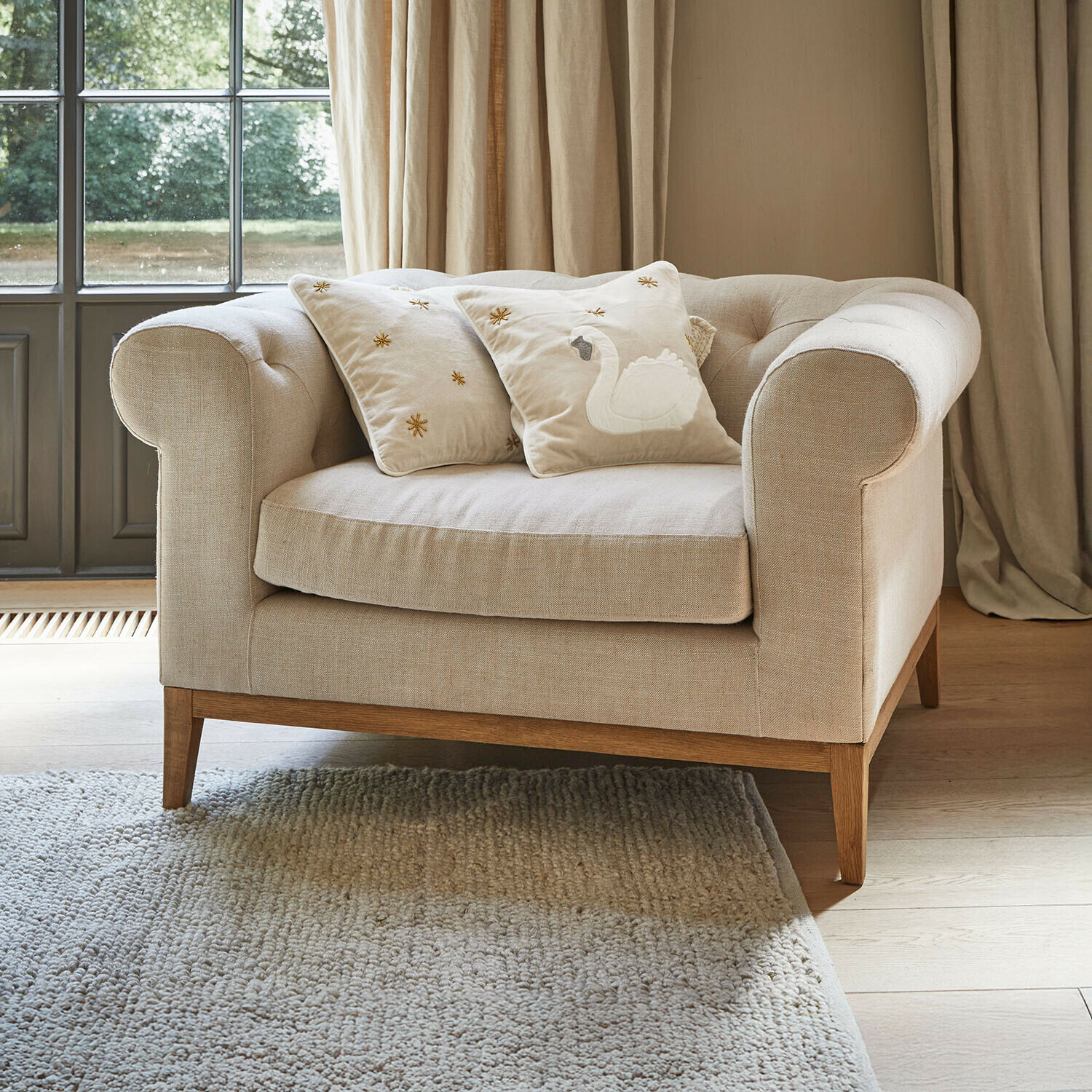 Poltrona Fairbourne Divano beige in tessuto con base in legno e due cuscini decorativi con ricamo a cigno
