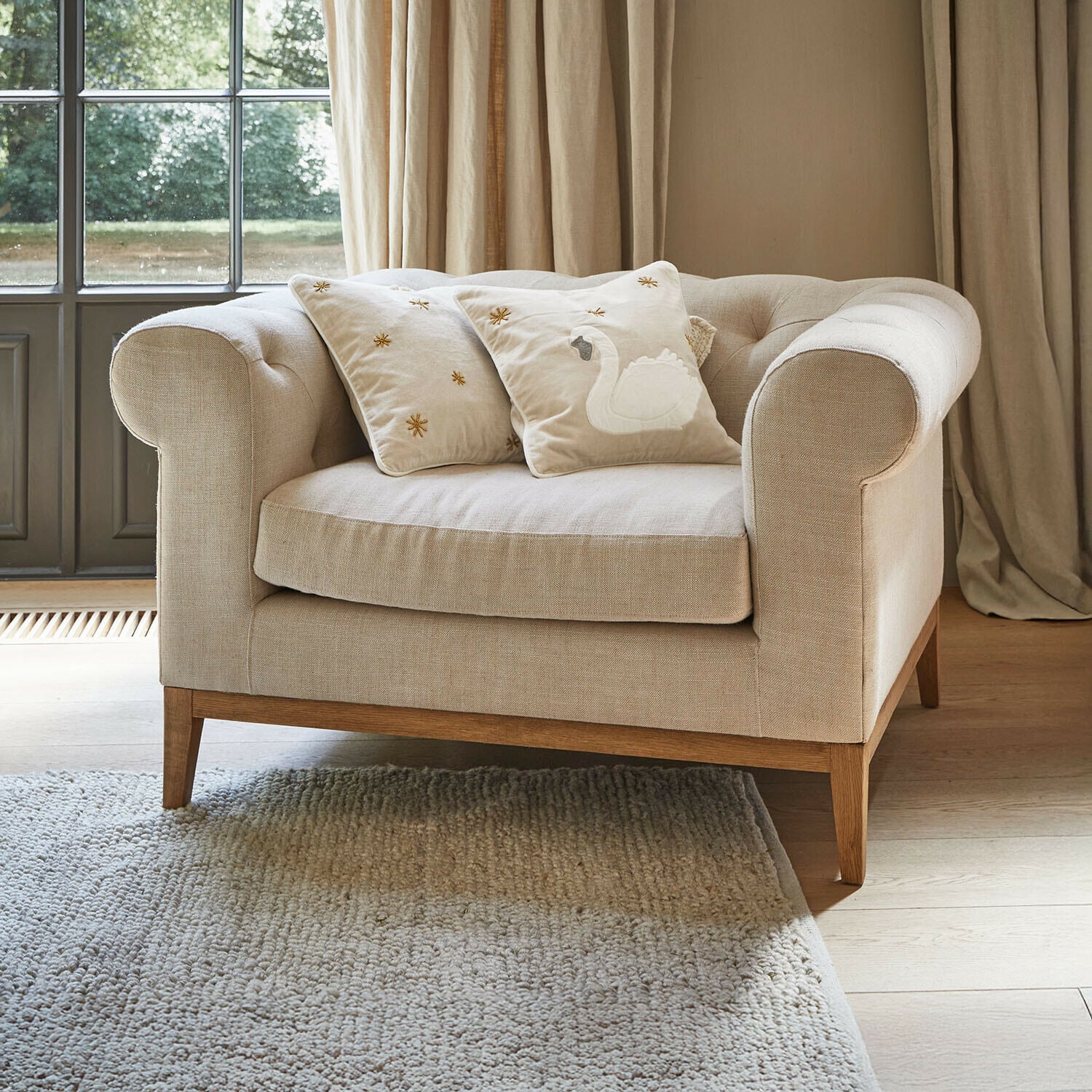 Poltrona Fairbourne Divano beige in tessuto con base in legno e due cuscini decorativi con ricamo a cigno