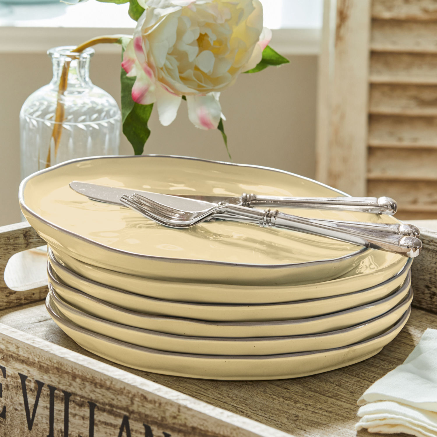 Set di 6 piatti Biarré Set di piatti in ceramica crema con bordo metallico e posate argentate su vassoio in legno