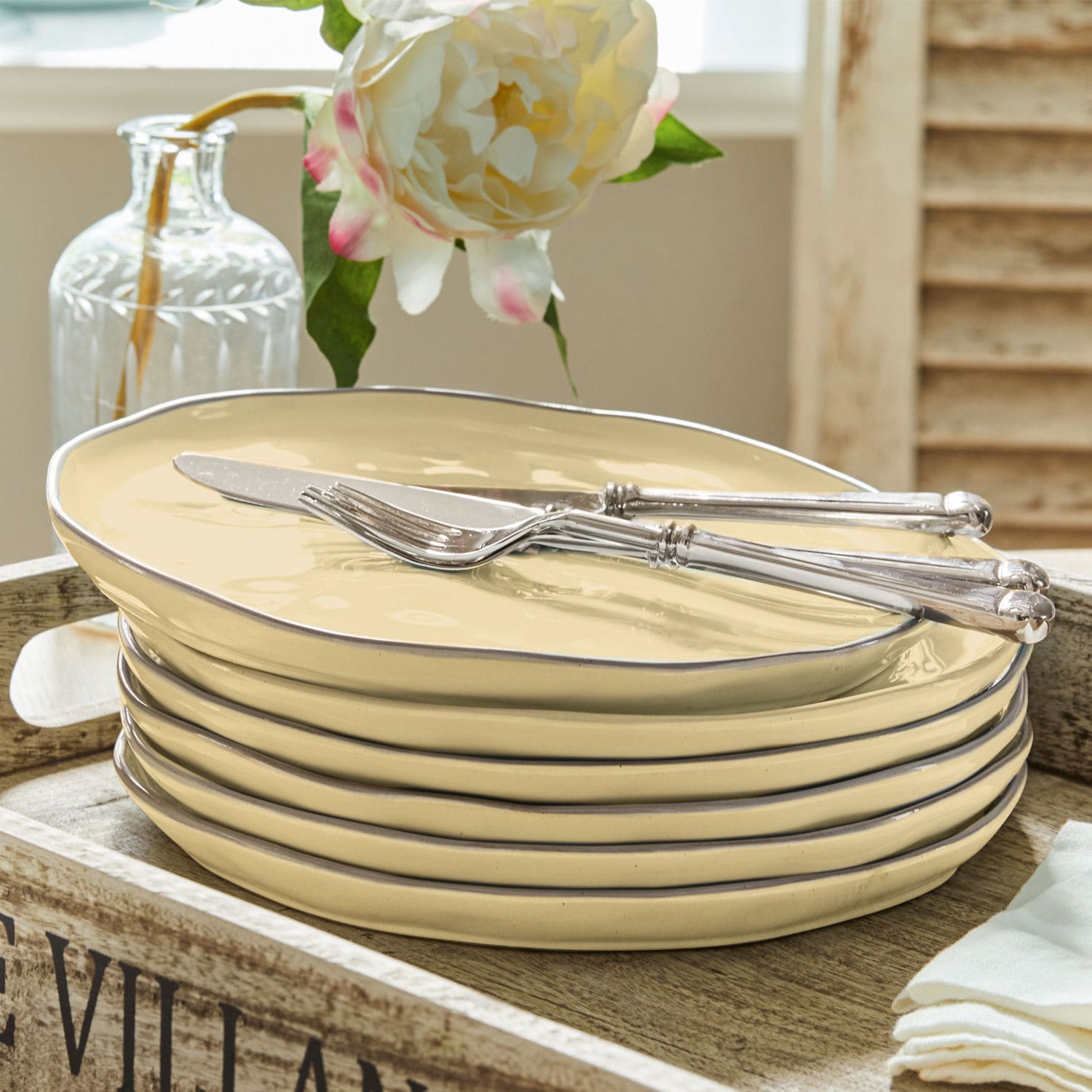 Set di 6 piatti Biarré Set di piatti in ceramica crema con bordo metallico e posate argentate su vassoio in legno
