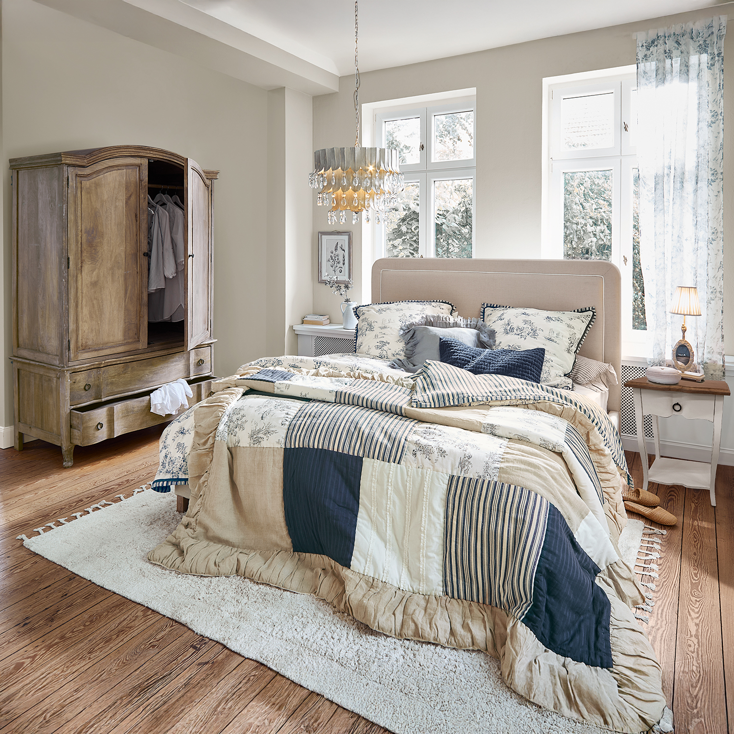 Camera da letto accogliente con copriletto patchwork beige e blu scuro, armadio in legno e tappeto morbido