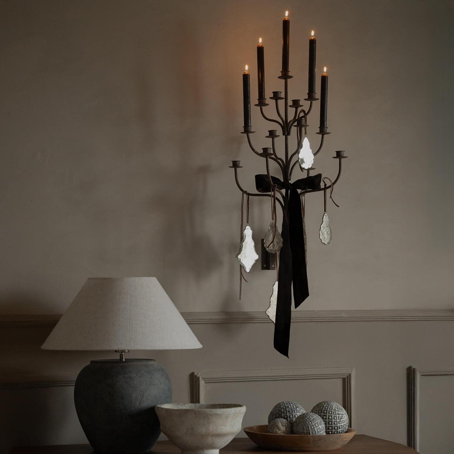 Applique da parete in metallo con candele nere e decorazioni vintage su parete beige in ambiente accogliente