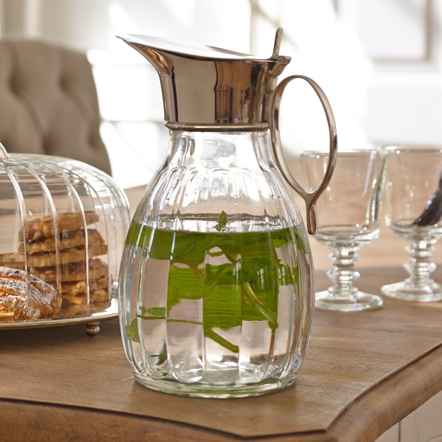 Caraffa Agudelle Caraffa in vetro con coperchio e manico in metallo, acqua con foglie di menta su tavolo con dolci