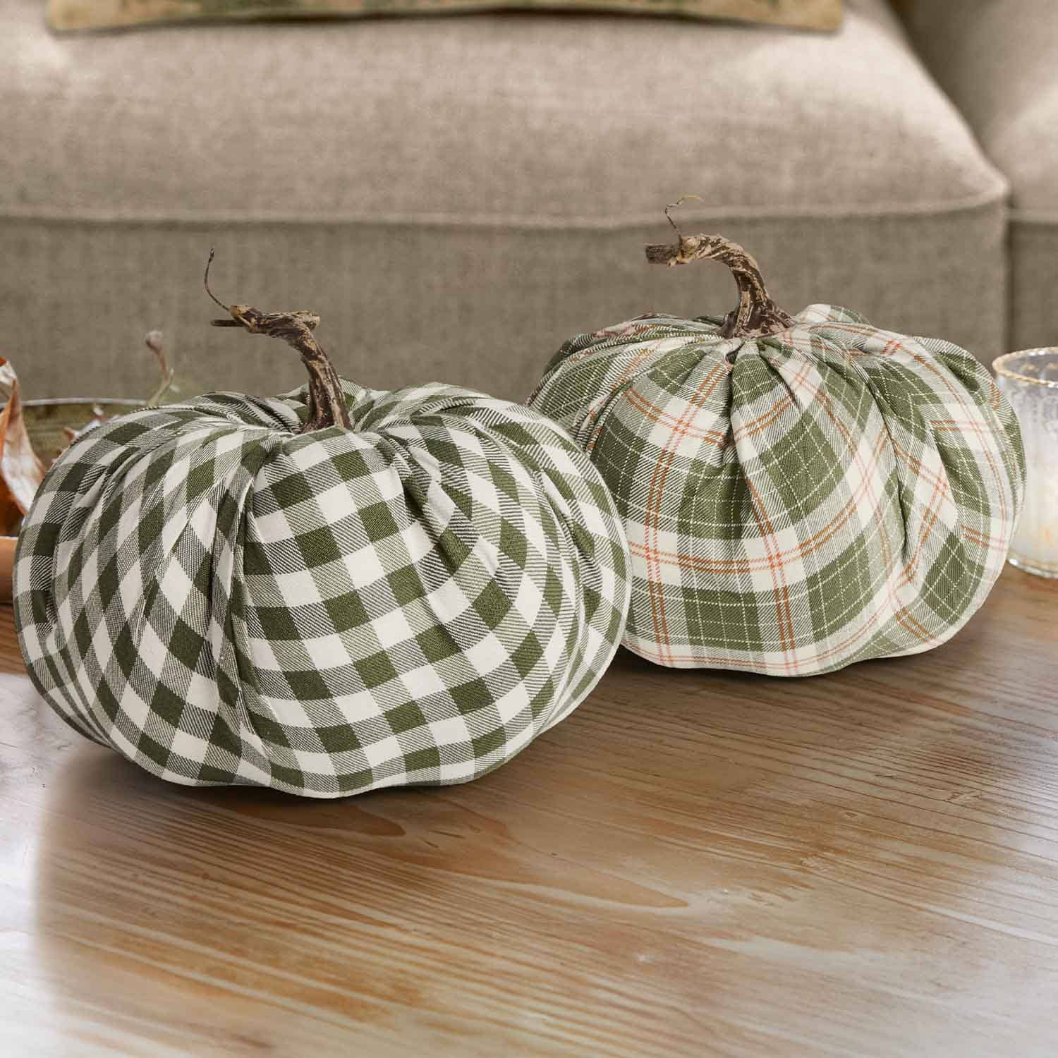 Due zucche decorative in tessuto a quadri verde e bianco con gambi naturali su tavolo in legno