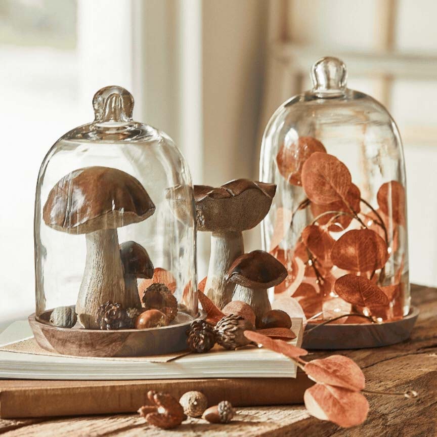 Funghi decorativi e foglie sotto campane di vetro su base in legno, decorazione autunnale per tavolo