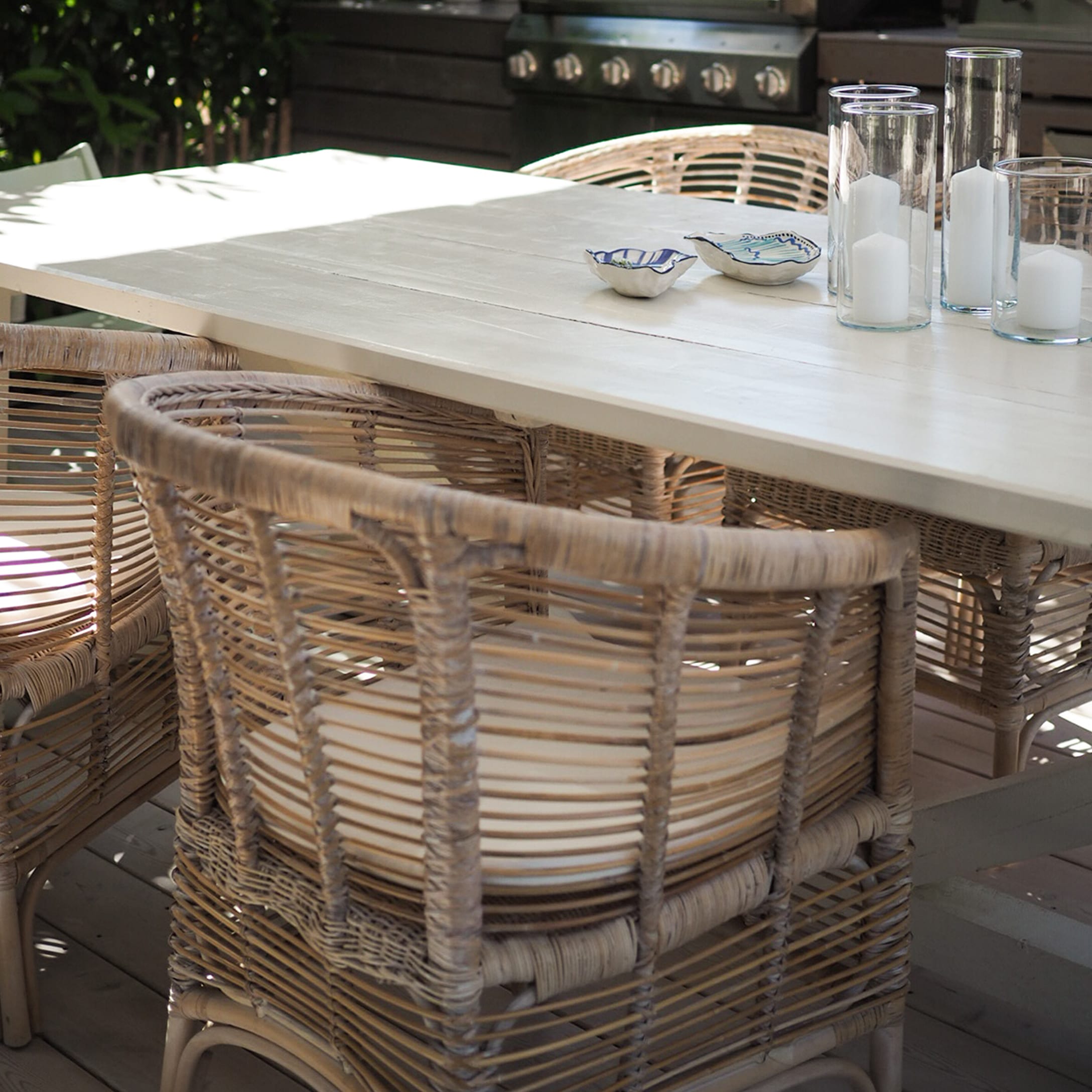 Tavolo da giardino in legno chiaro con sedie in vimini e candele decorative sulla terrazza