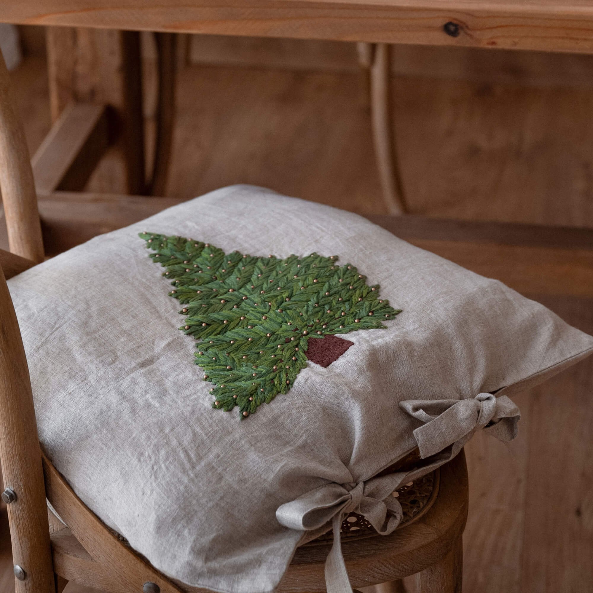 Cuscino beige in lino per sedia con ricamo di albero di Natale verde e fiocchi laterali