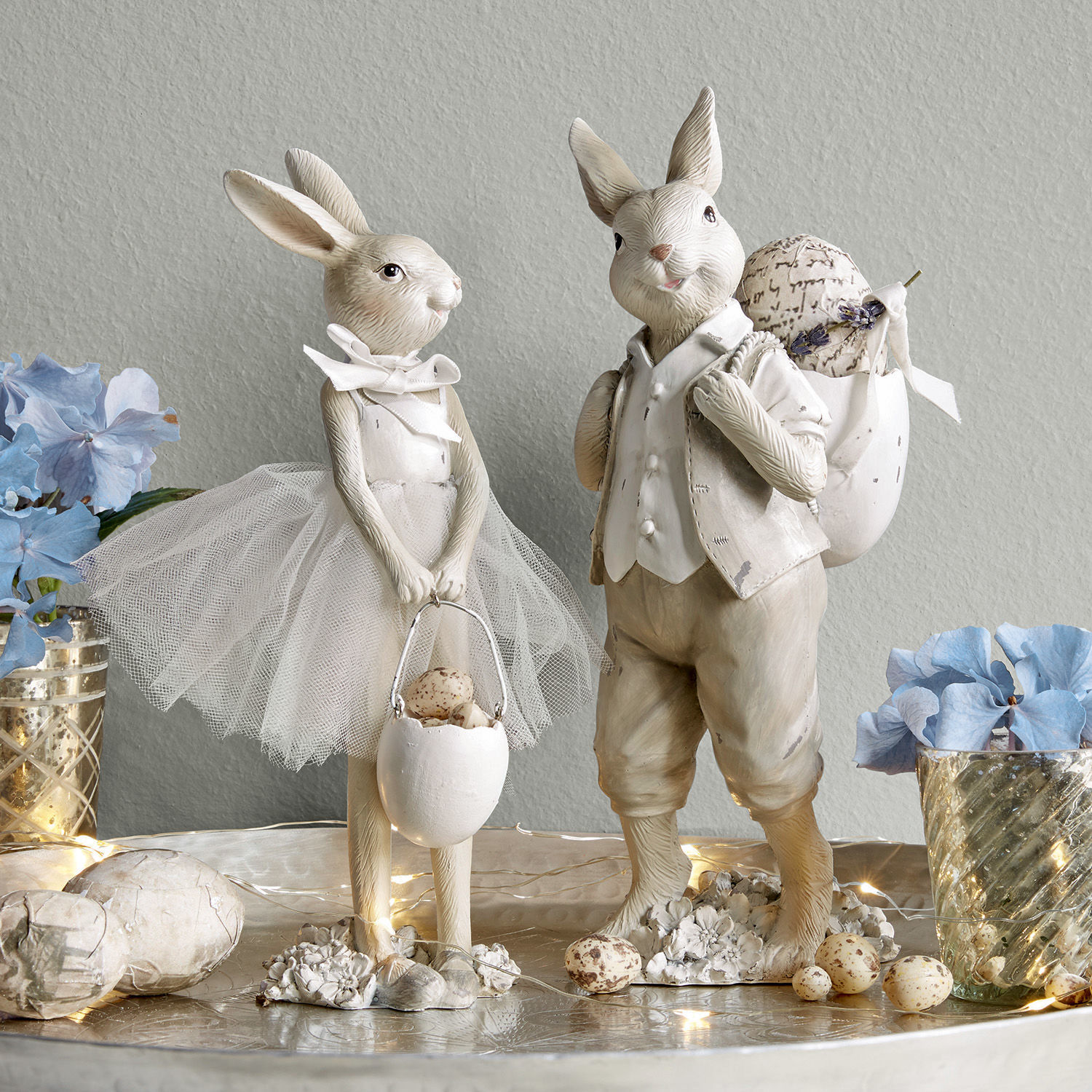 Coppia di coniglietti Perpignan Figure decorative di conigli chiari con accessori pasquali e fiori su un tavolo