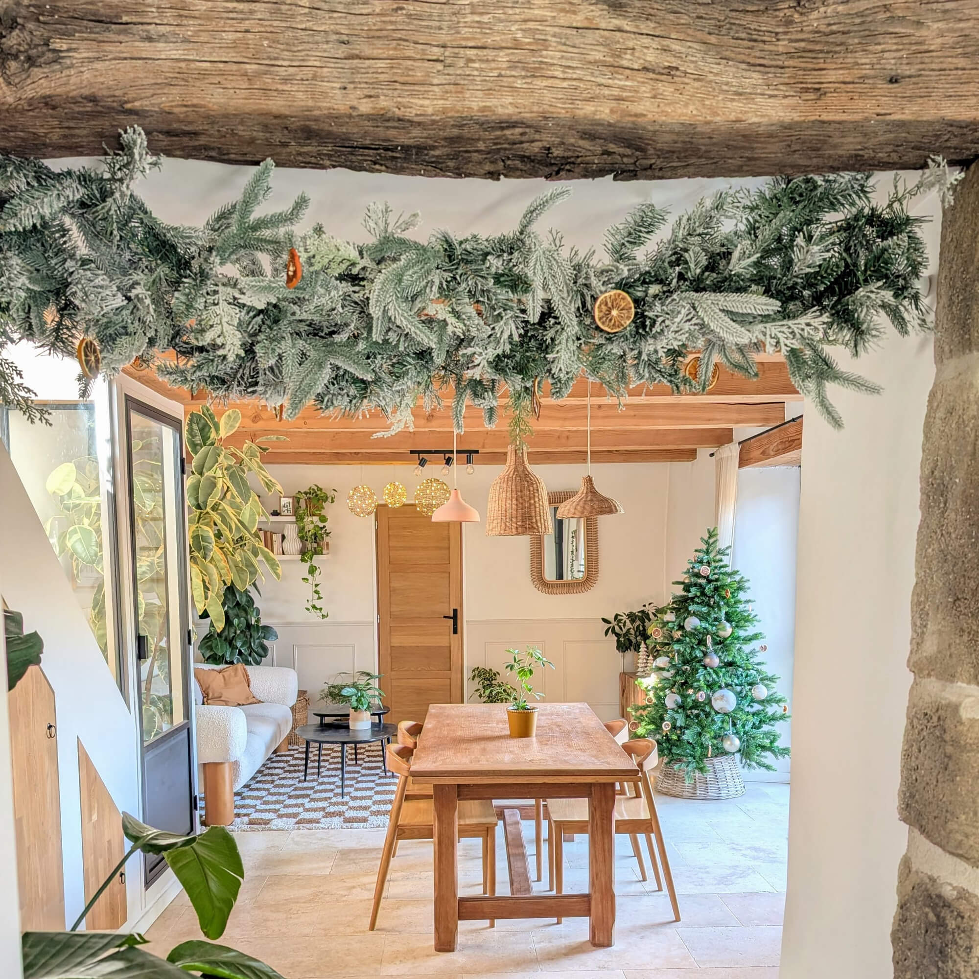 Accogliente sala da pranzo con tavolo in legno, albero di Natale verde e ghirlanda con fette di arancia essiccate