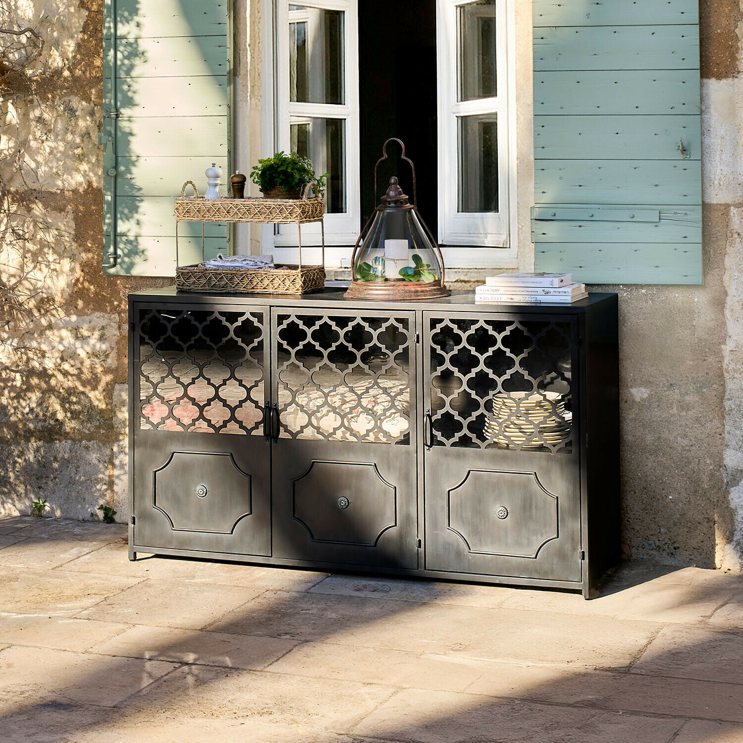 Credenza bassa Astralon Credenza nera in metallo con ante traforate su terrazza davanti a finestra con persiane verdi
