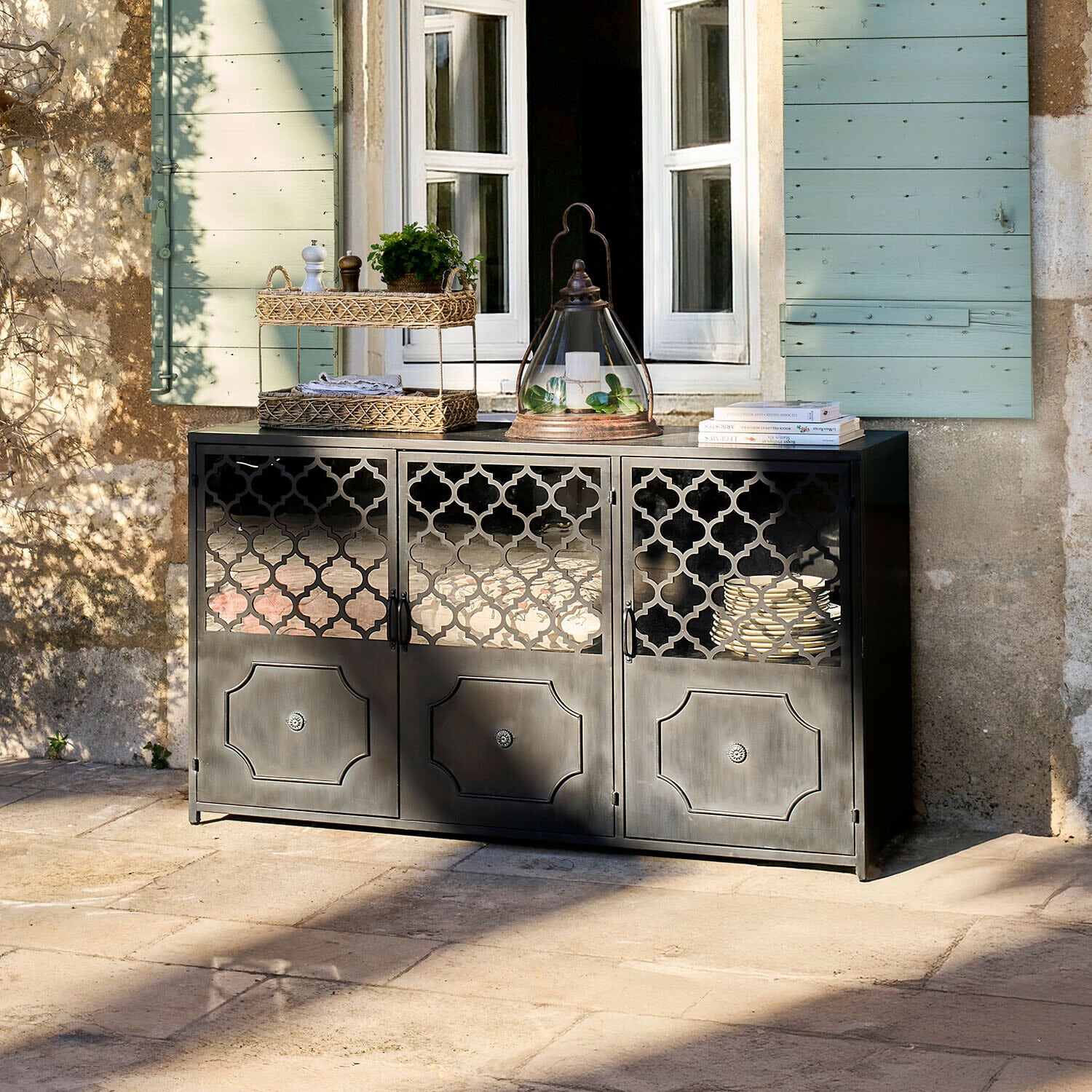 Credenza bassa Astralon Credenza nera in metallo con ante traforate su terrazza davanti a finestra con persiane verdi