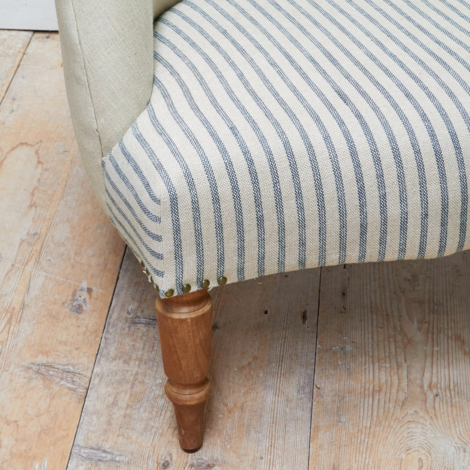 Gamba di mobile in legno con rivestimento beige a righe blu su pavimento in legno