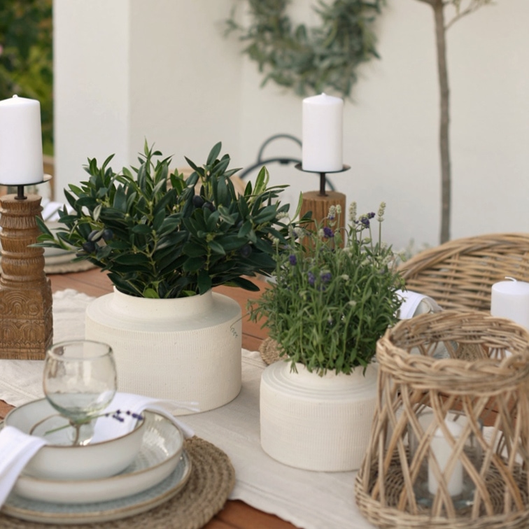 Vasi in ceramica bianca con piante verdi su tavolo in legno con candelabri naturali