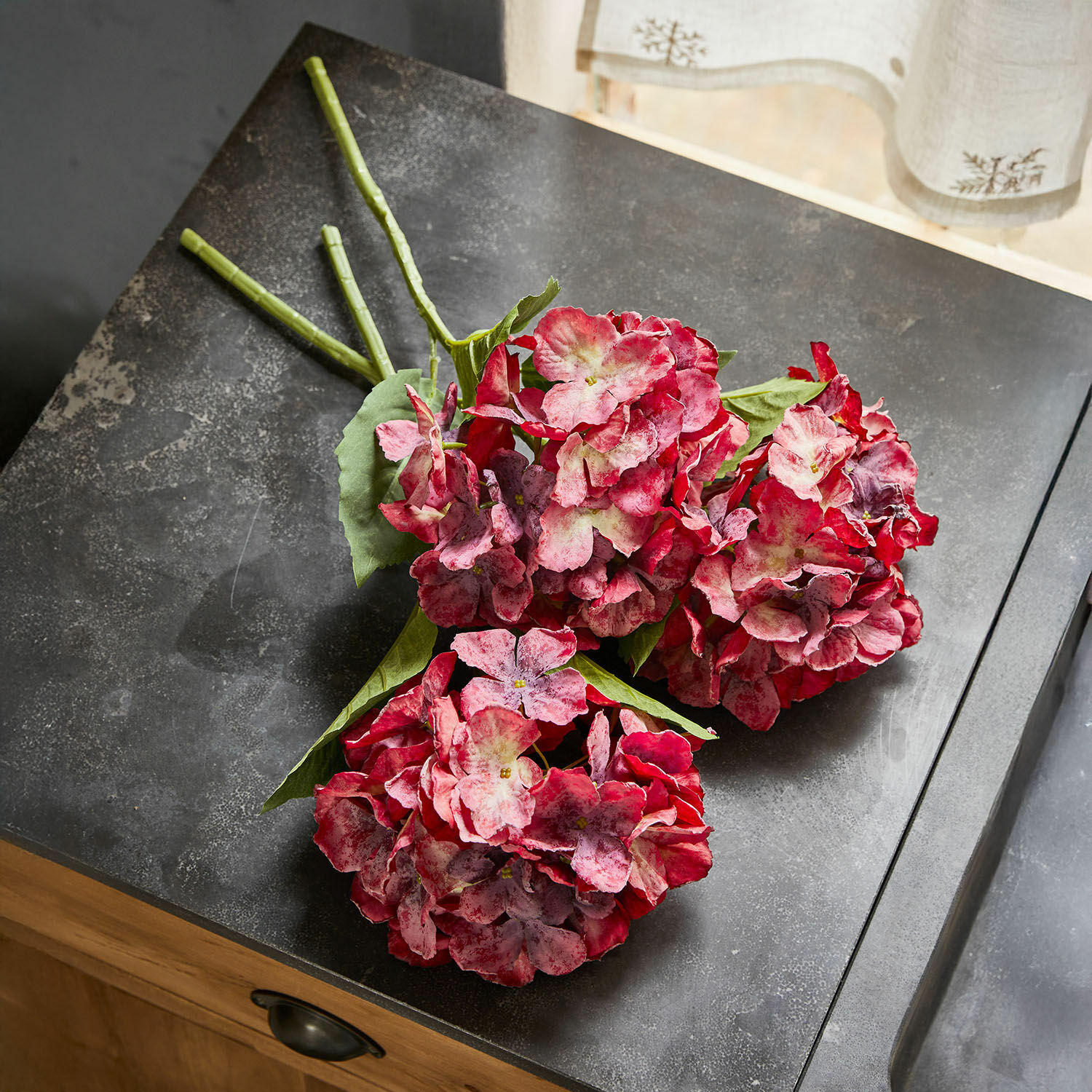 Set di 3 fiori decorativi Virette Mazetto di ortensie artificiali rosso-rosa con foglie verdi su superficie scura