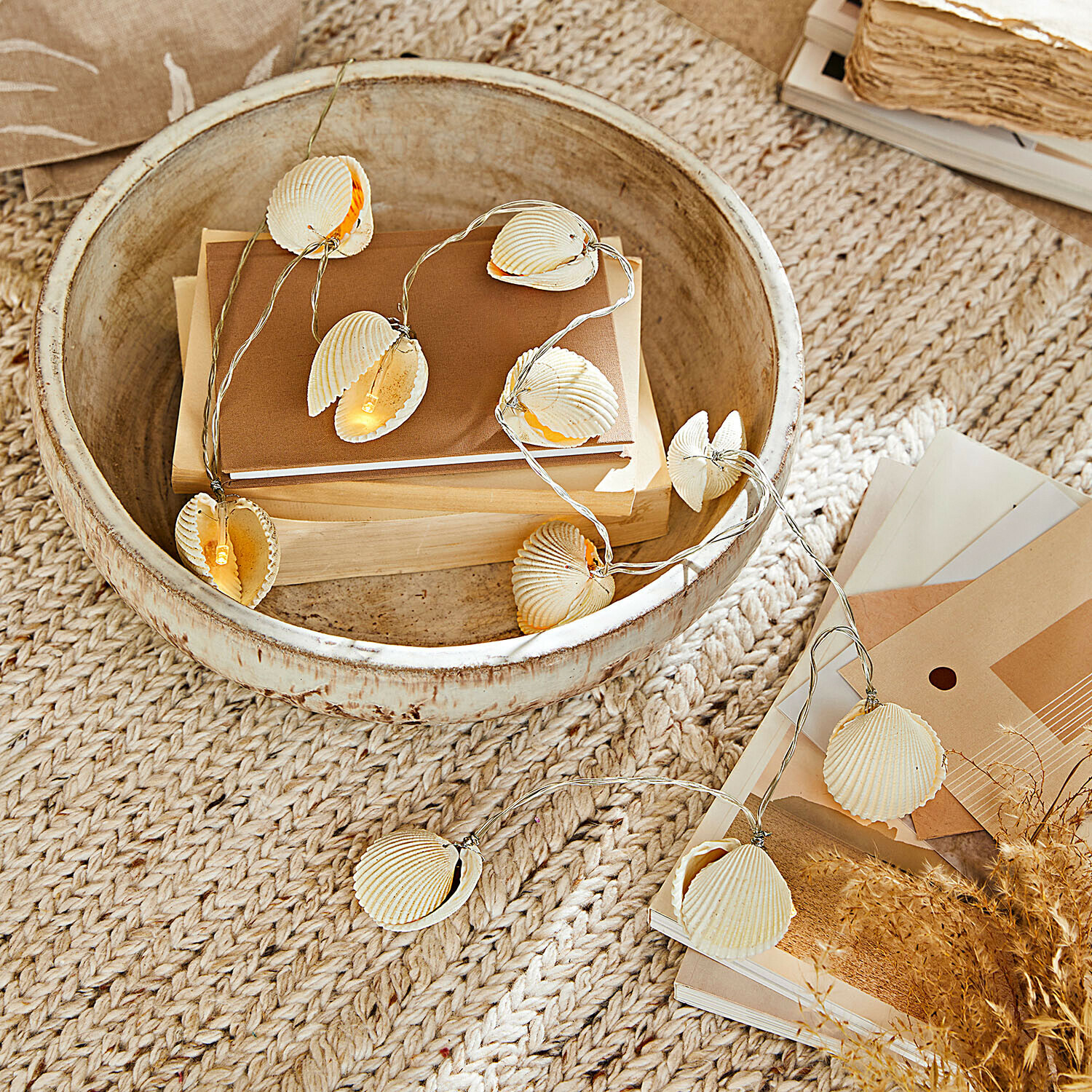 Catena luminosa Havenor Ghirlanda luminosa con conchiglie naturali beige su ciotola di legno con libri e decorazioni