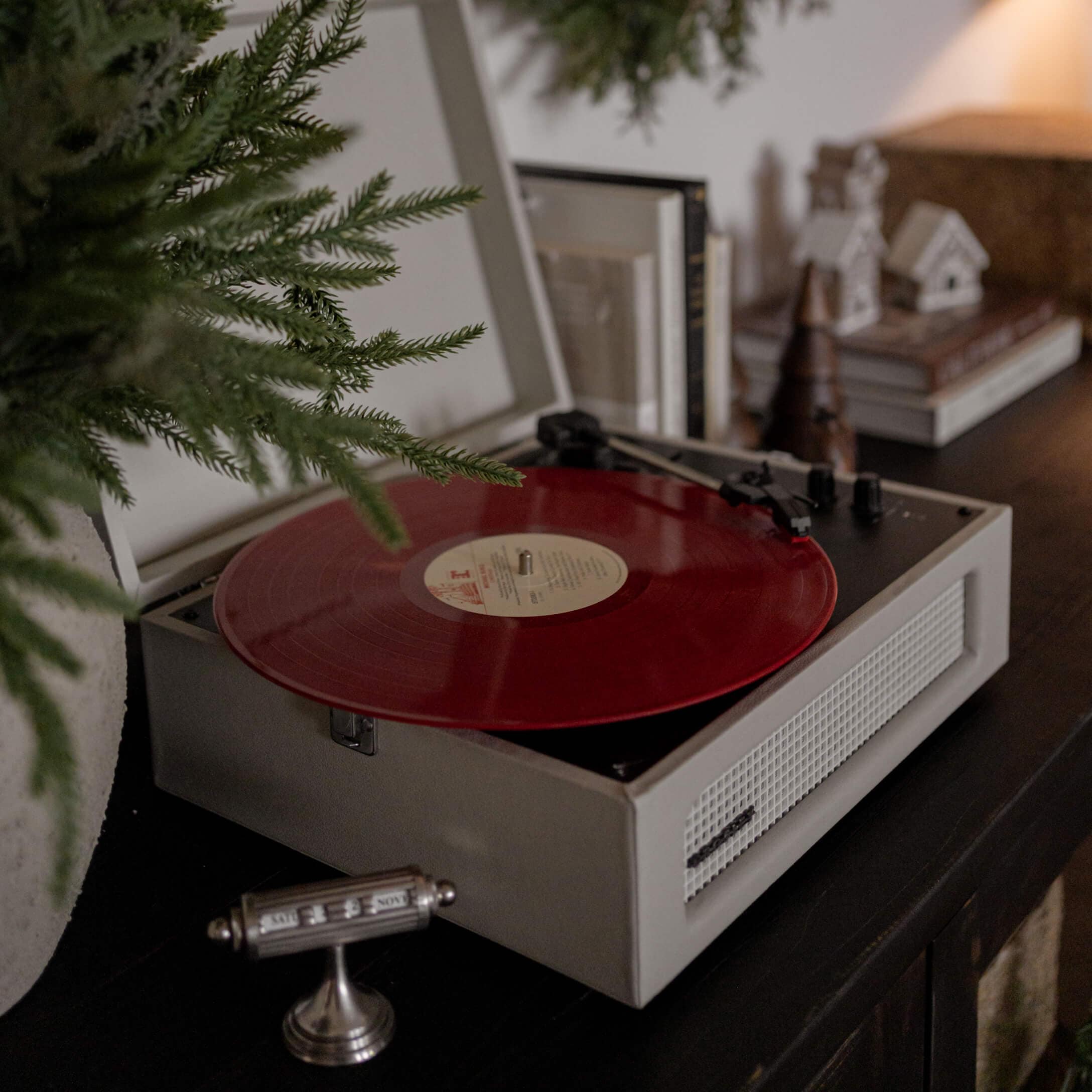 Giradischi vintage con disco in vinile rosso su mobile scuro in ambiente accogliente