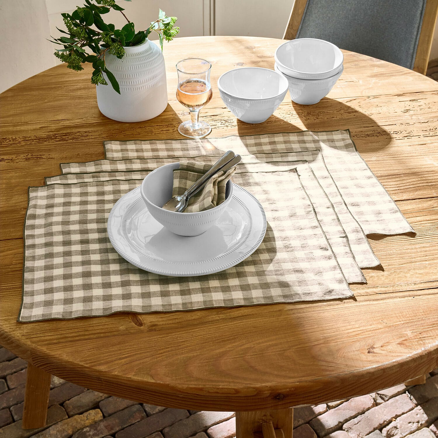 Set di 4 tovagliette Marrowby Ciotole e piatto in ceramica bianca su tavolo in legno con tovagliette in lino beige a quadri