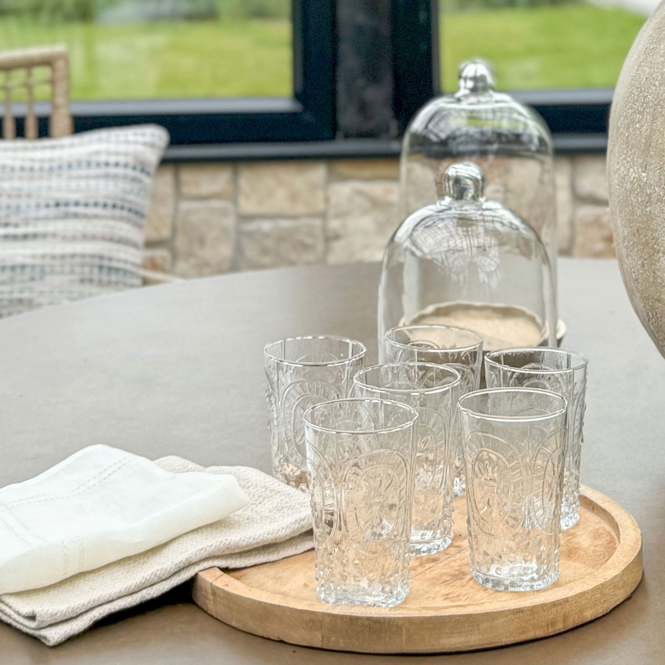 Set di sei bicchieri trasparenti con motivo decorativo su vassoio in legno per servire bevande