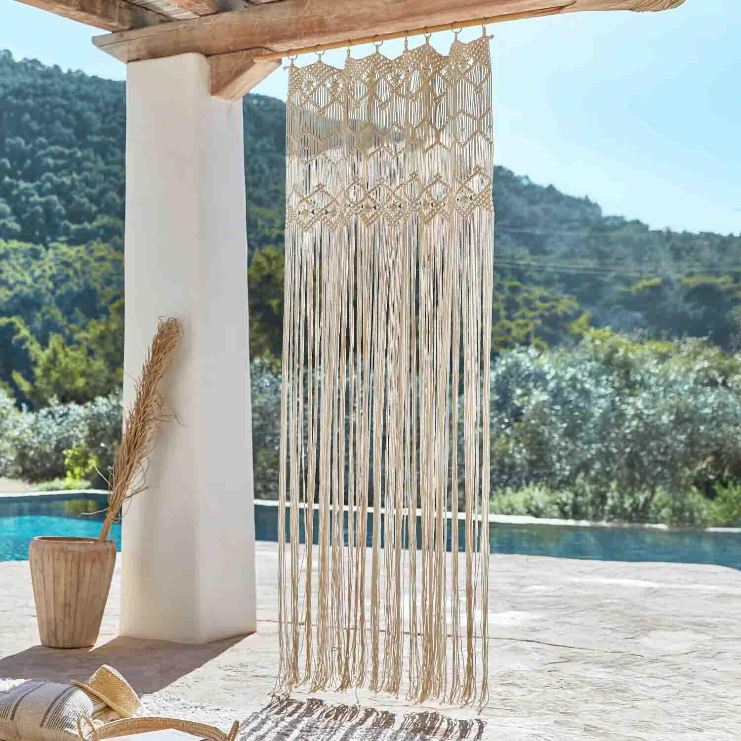 Macramè beige in cotone appeso a trave di legno, decorazione boho per terrazza con vista piscina