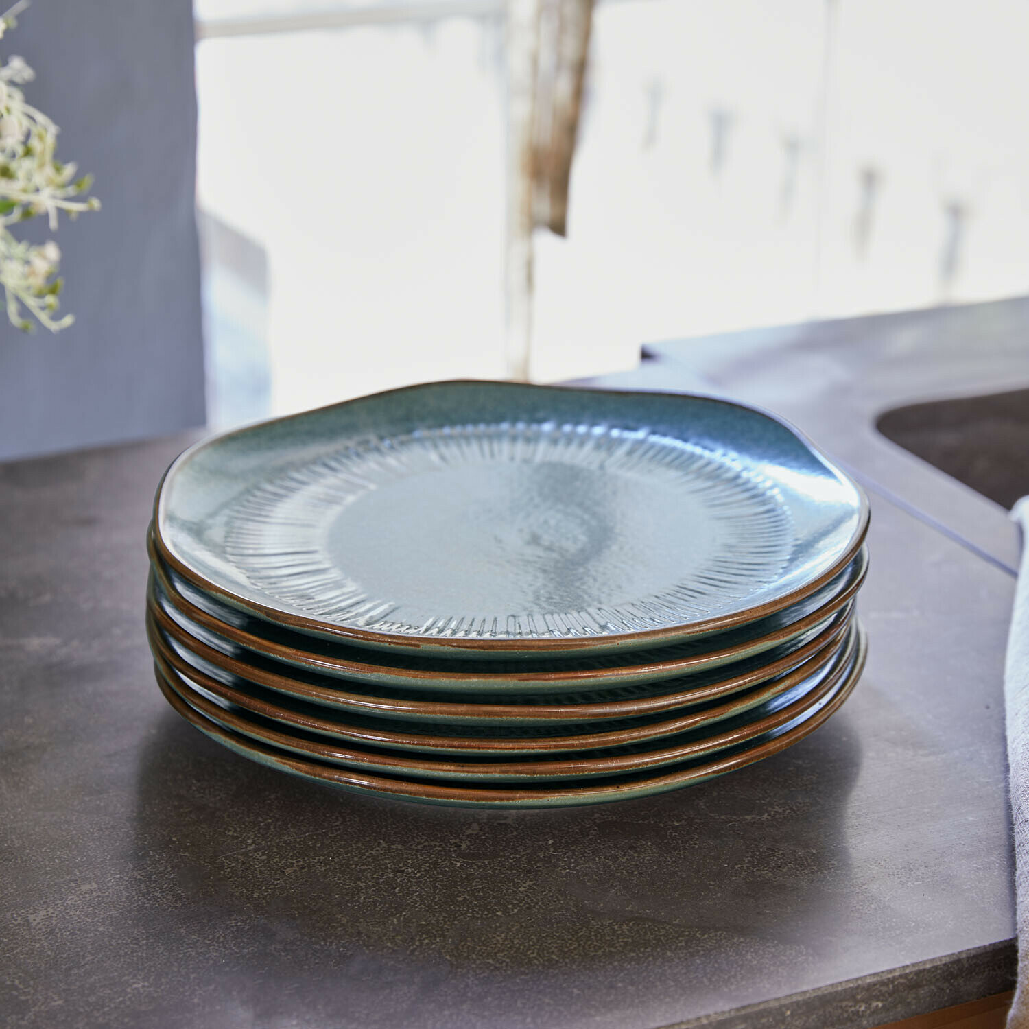 Set di 6 piattini Périers Set di sei piatti in ceramica verde con bordo marrone impilati su piano cucina