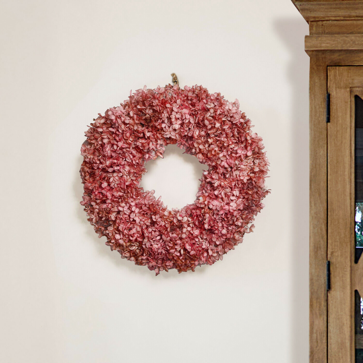 Corona decorativa di fiori secchi rosa appesa al muro per arredamento interno