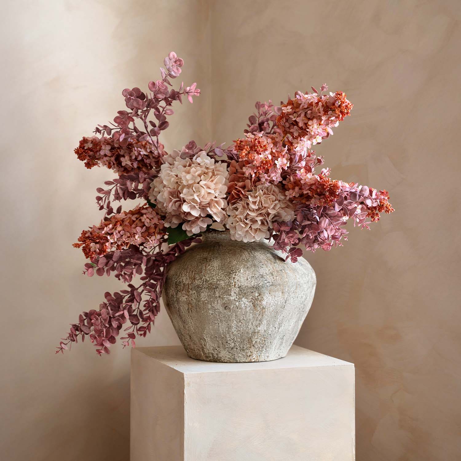 Vaso rustico in pietra con mazzo di fiori decorativi rosa e beige per arredamento interno