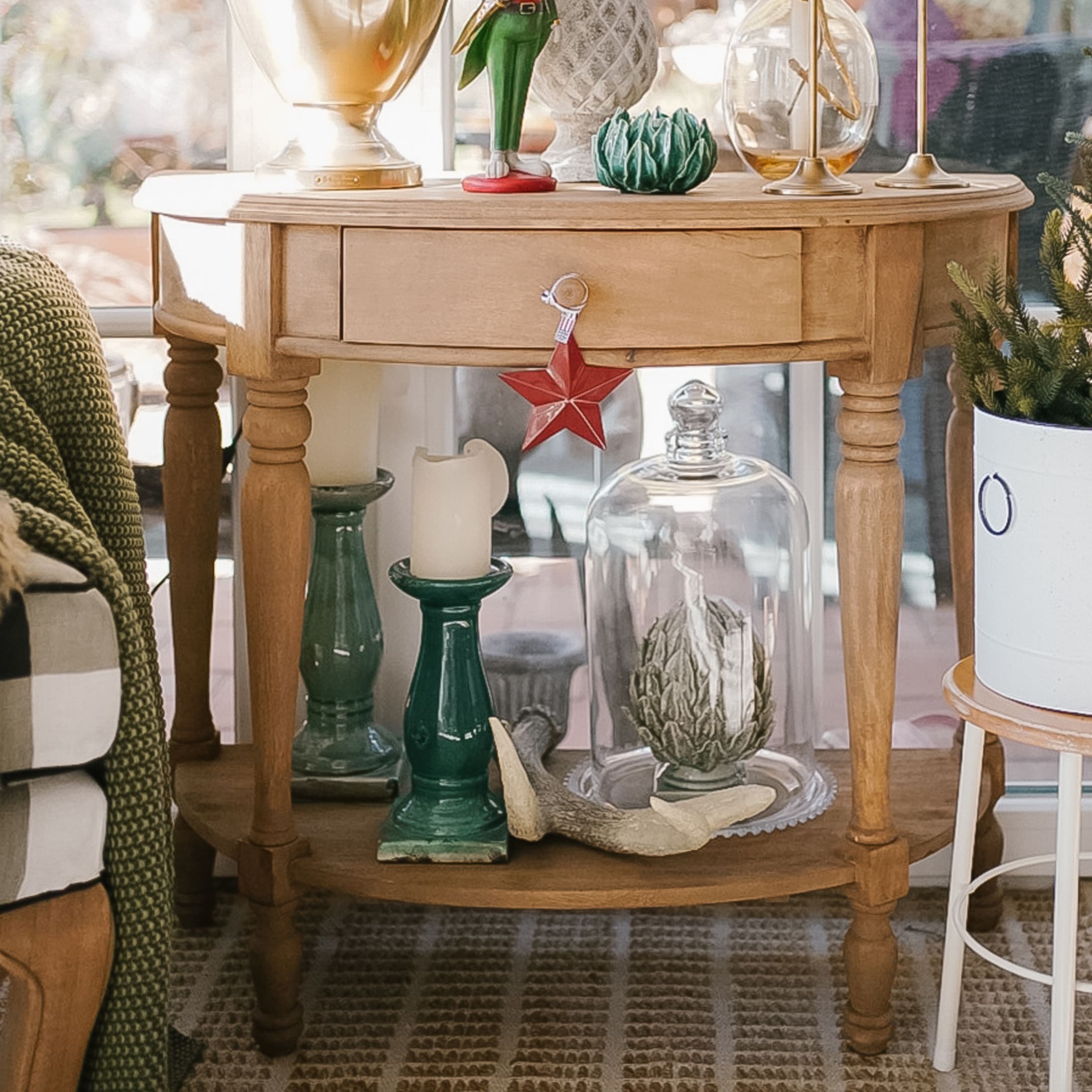 Tavolino in legno con decorazioni natalizie, portacandele verdi e oggetto decorativo sotto campana di vetro