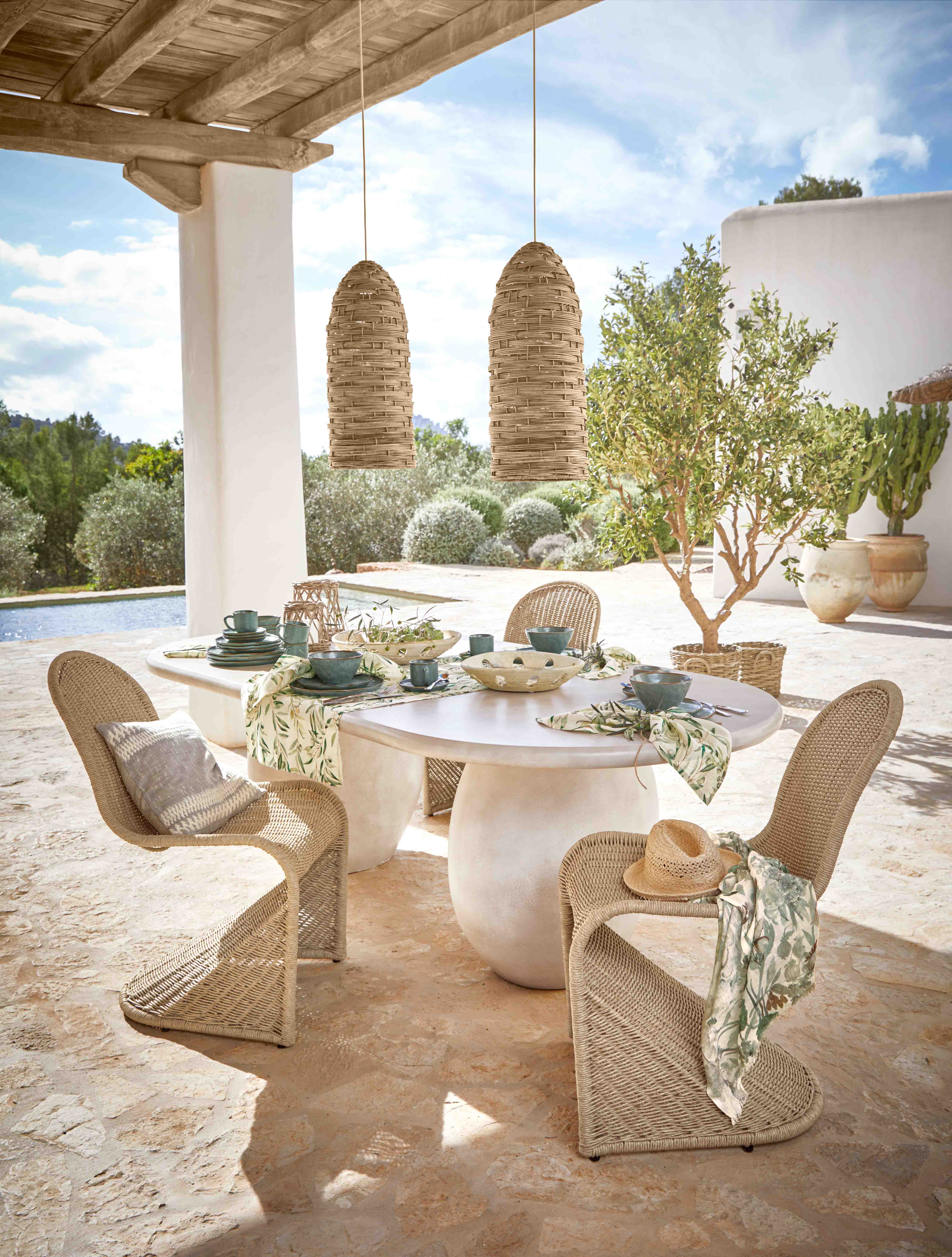 Set di mobili da giardino in vimini con sedie e tavolo bianco su terrazza con decorazioni
