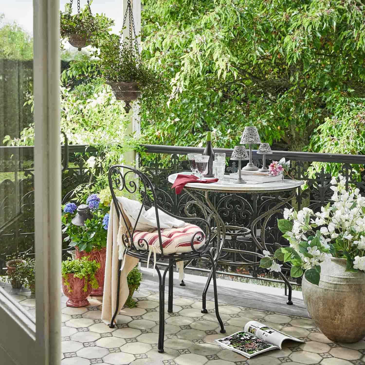 Balcone con tavolo e sedia in metallo, piante in vaso e atmosfera rilassante all'aperto