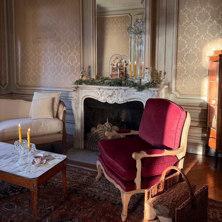 Soggiorno classico con poltrona bordeaux in legno e tavolo in marmo con candele accese