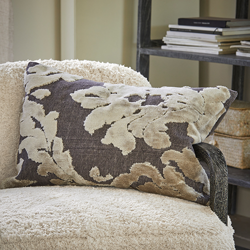 Cuscino decorativo con motivo foglie beige su sfondo grigio su poltrona crema, tessile per la casa