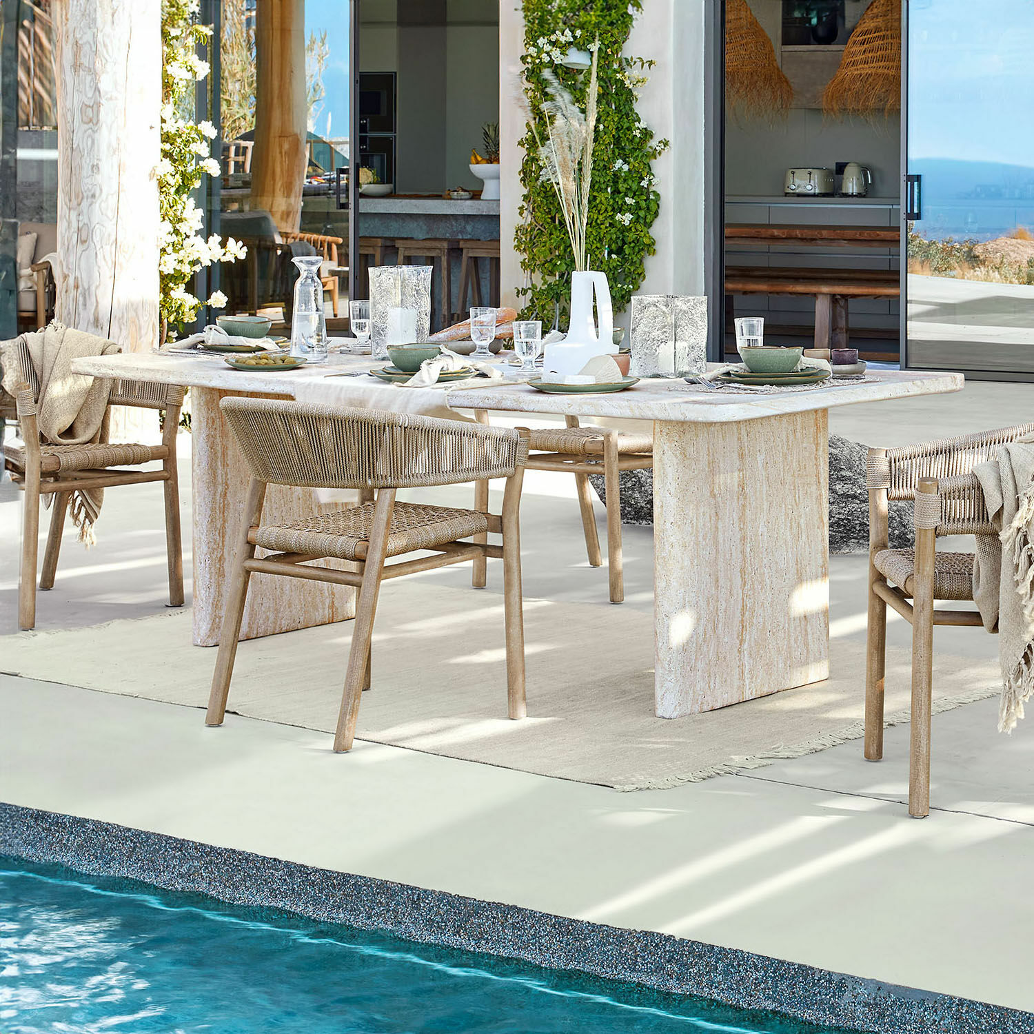 Tavolo da pranzo Yveline Tavolo da pranzo in pietra chiara con sedie in legno intrecciato vicino a piscina in casa moderna