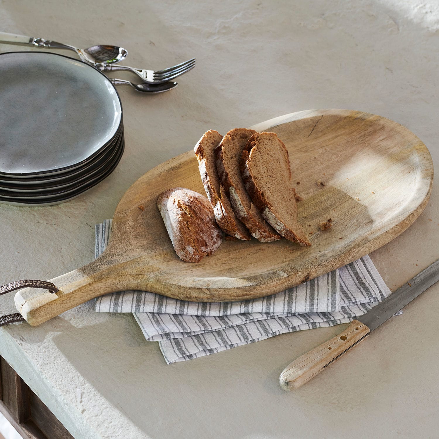 Vassoio Journée Tagliere in legno con manico e fette di pane su piano cucina grigio chiaro