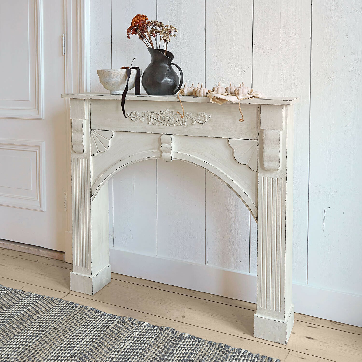 Consolle caminetto Maxwell Consolle in legno bianco con intagli decorativi e vaso nero con fiori secchi sopra