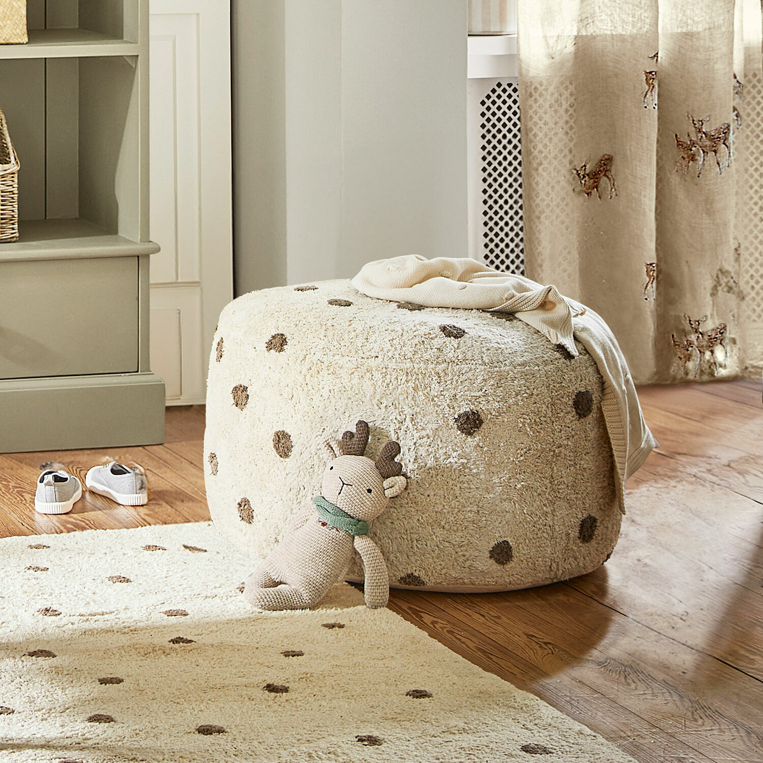 Pouf Thivalie Pouf beige morbido a pois su pavimento in legno con peluche e tappeto coordinato