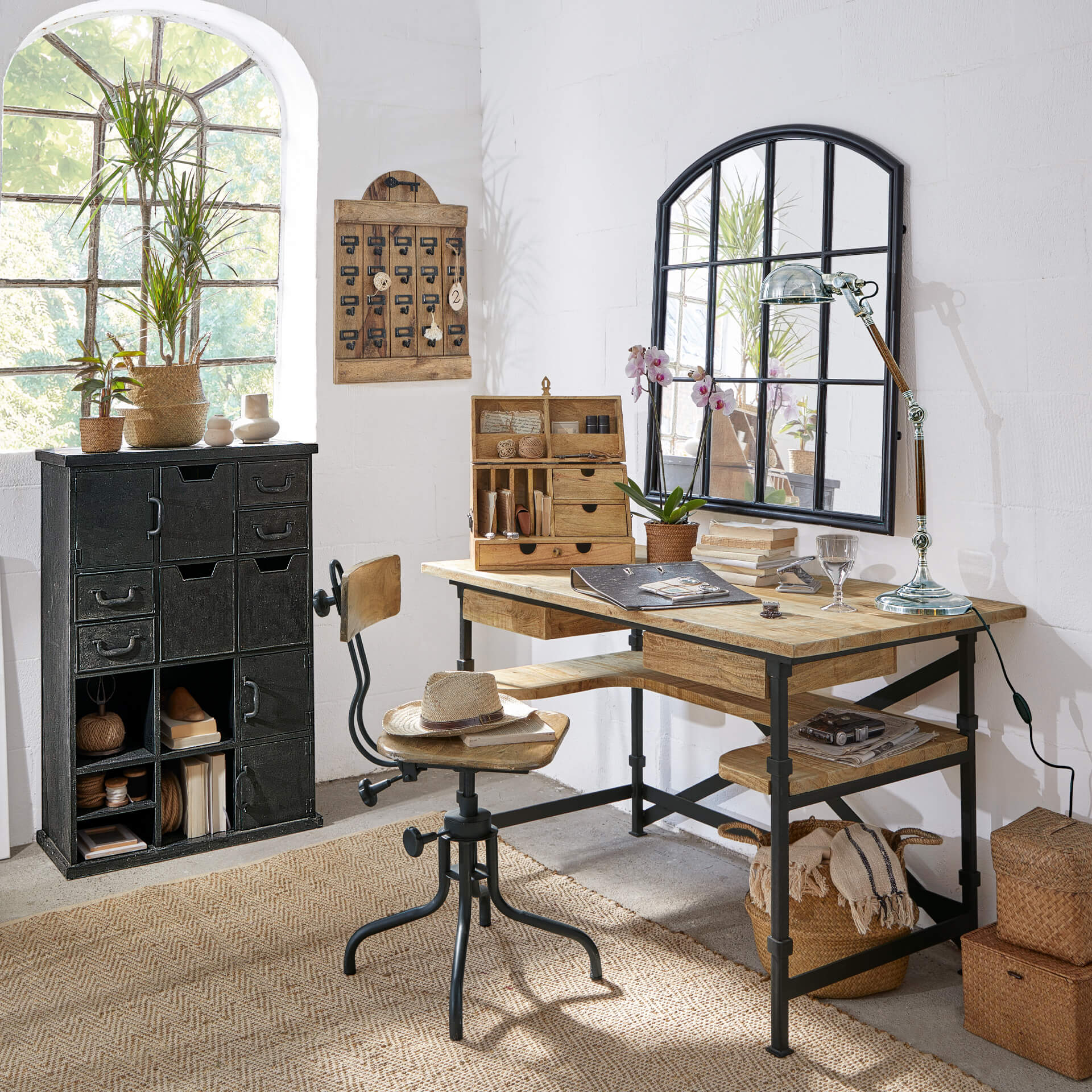 Scrivania e sedia in legno e metallo stile industriale in stanza luminosa con decorazioni e specchio