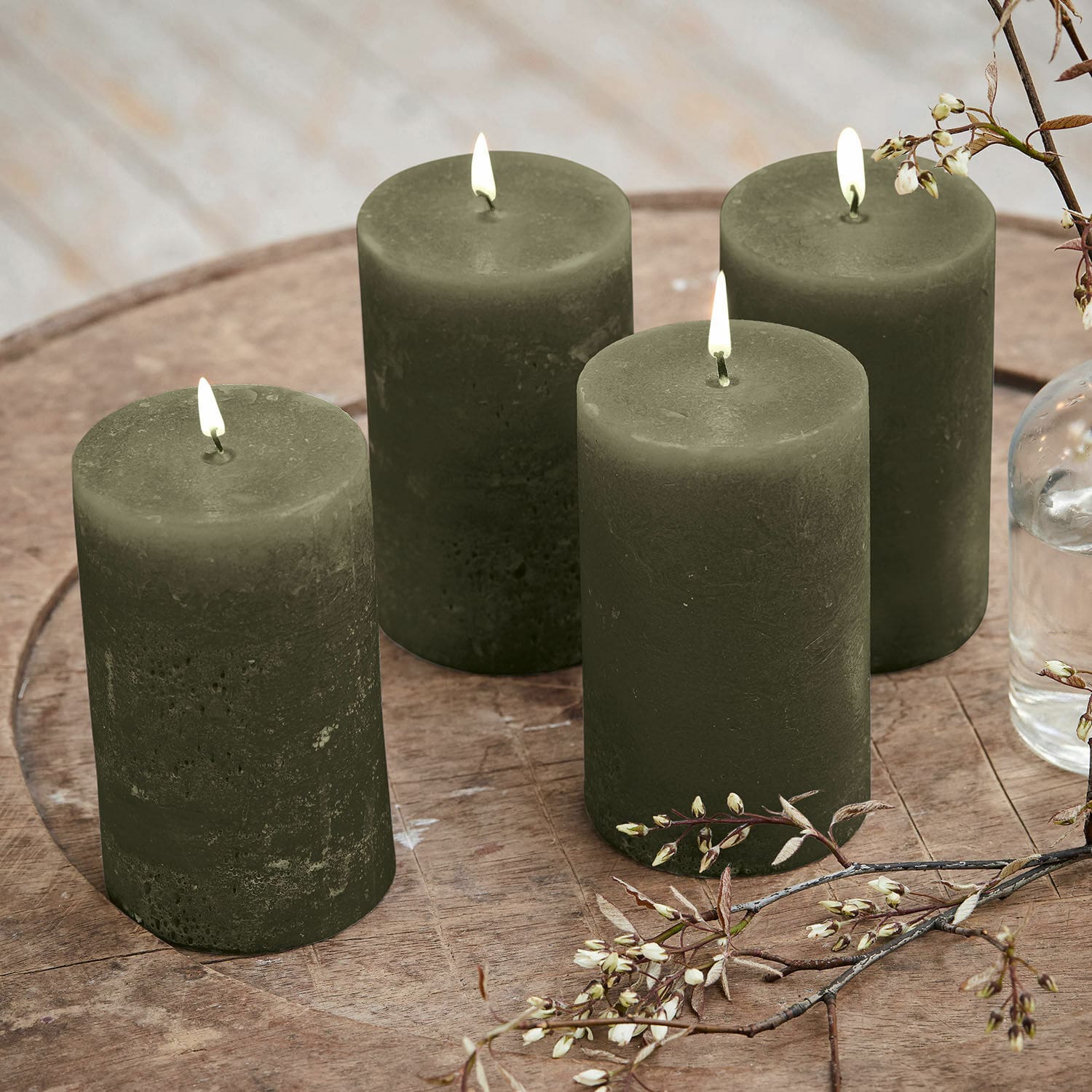 Set di 4 candele Braga Set di quattro candele verdi in cera su tavolo di legno con decorazione floreale