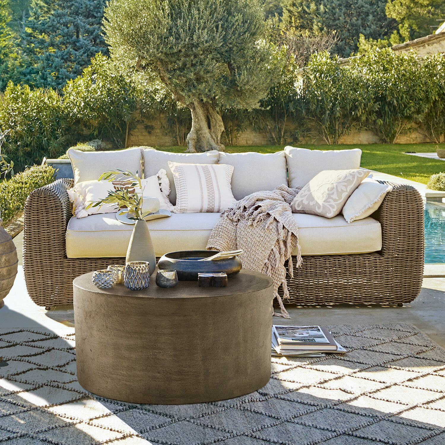 Divano Bogdanne Divano da giardino in rattan beige con cuscini e tavolino rotondo in cemento su tappeto