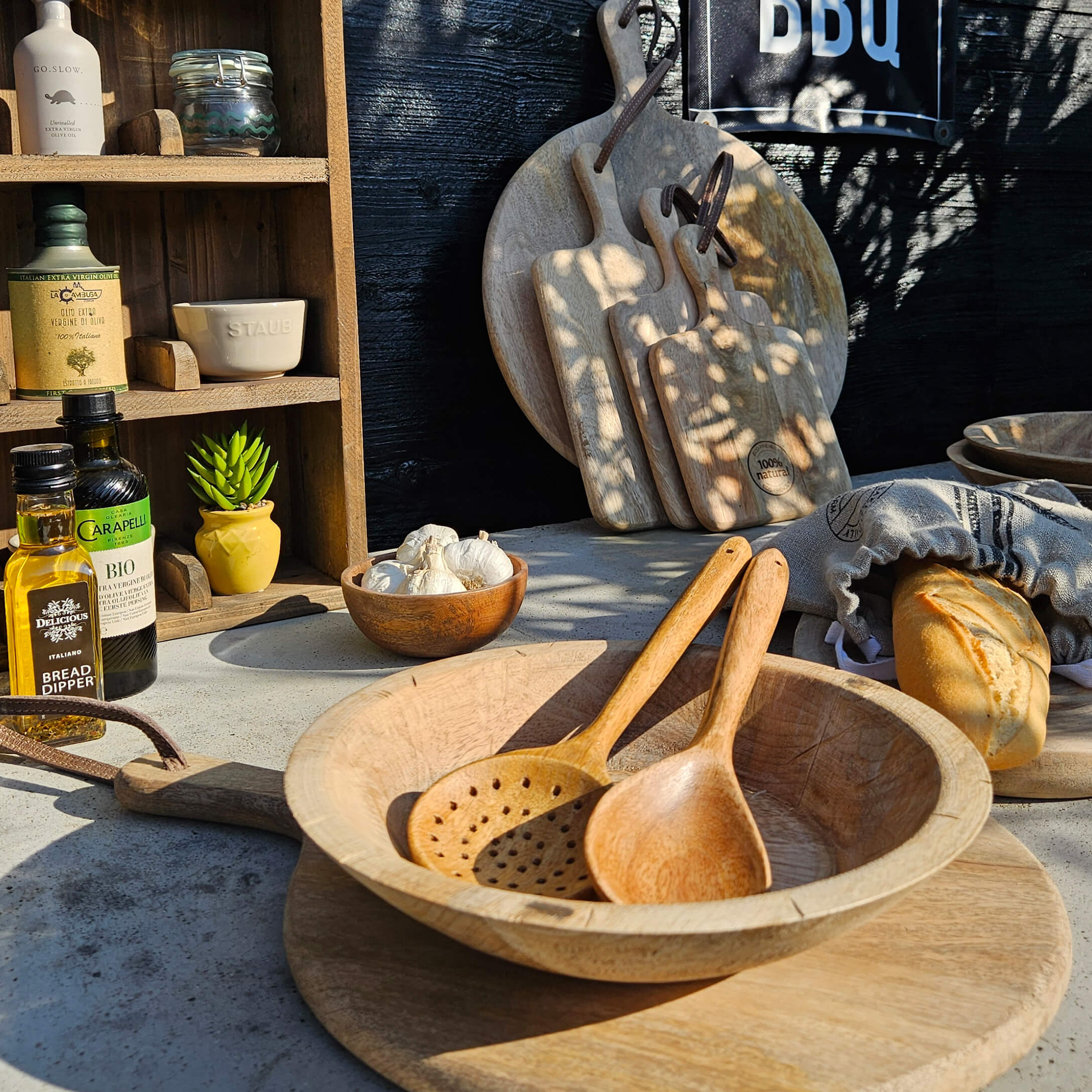 Set di taglieri e cucchiai in legno su tavolo con pane e olio d'oliva