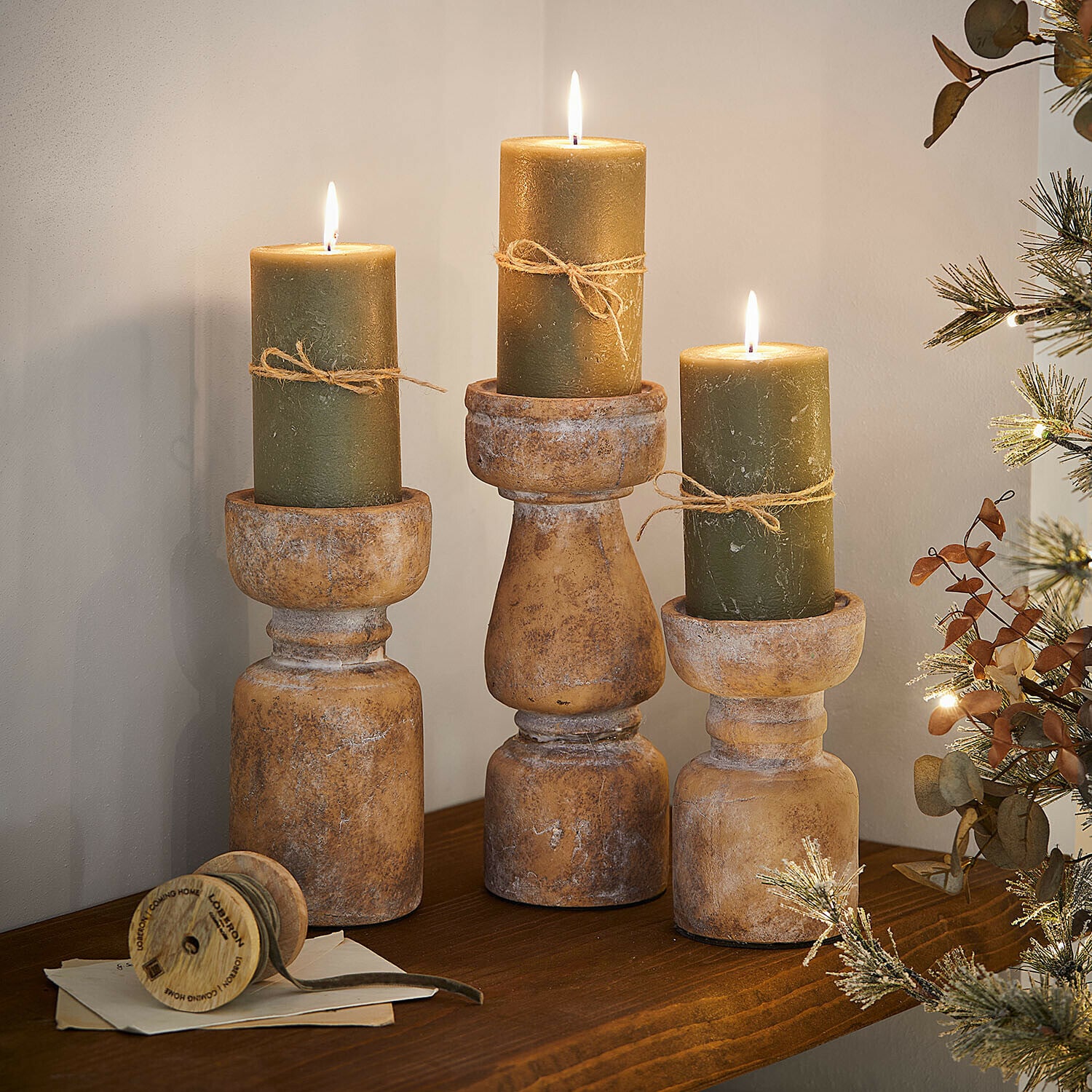 Set di 3 candelieri Talona Tre portacandele rustici in legno con candele verdi e spago su mensola decorativa in legno
